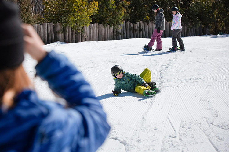 a child laying on the snow after falling over