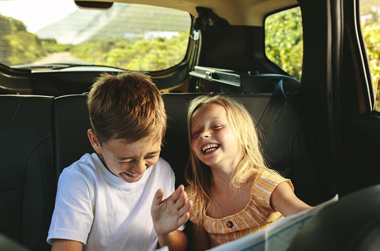 two kids sitting in a car laughing together
