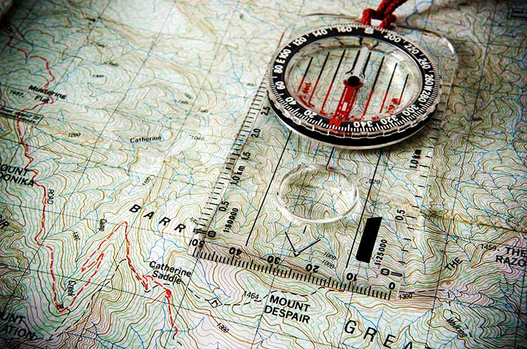 Orienteering compass sitting atop a map