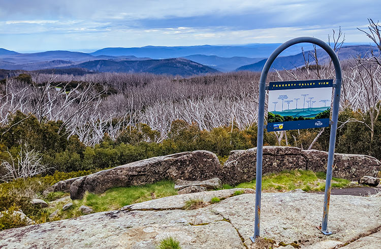 Information sign at rocky lookout with mountain landscape in background