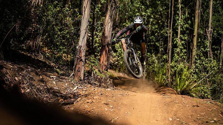 a guy riding a mountain bike on a dirt hill in the air after going over a jump