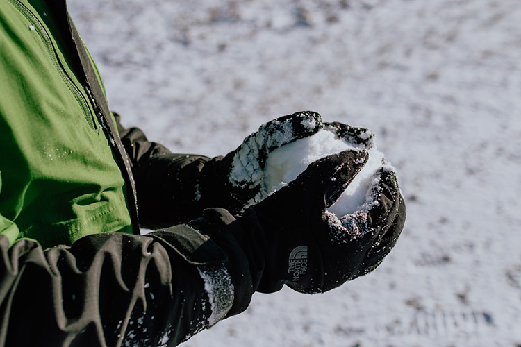 a kid wearing snow gloves holding a snowball
