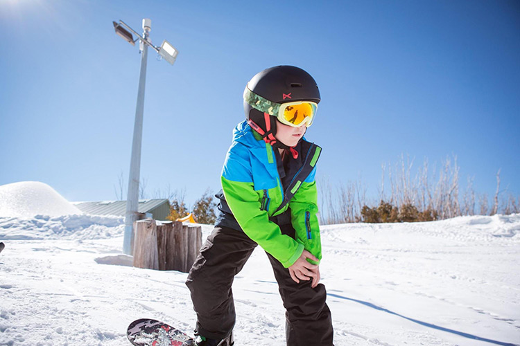 a boy wearing snow goggles riding down the mountain